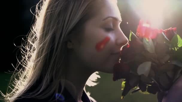 women smelling on red roses