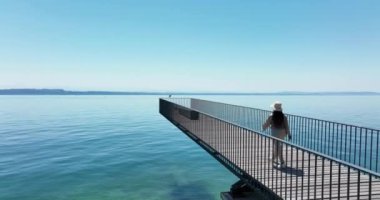 Aerial video of happy carefree woman standing on pier and looking at sea