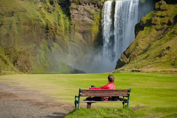 Turist tar resten på bänken mot stora vattenfall — Stockfoto