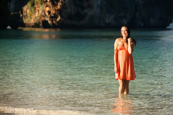 Smiling girl in a dress stands in the water blue sea — Stock Photo, Image