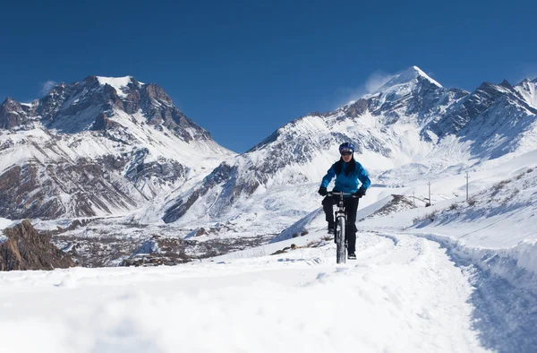 Chica en bicicleta paseos en la nieve en las altas montañas del Himalaya. Annapurna pista Himalaya — Foto de Stock