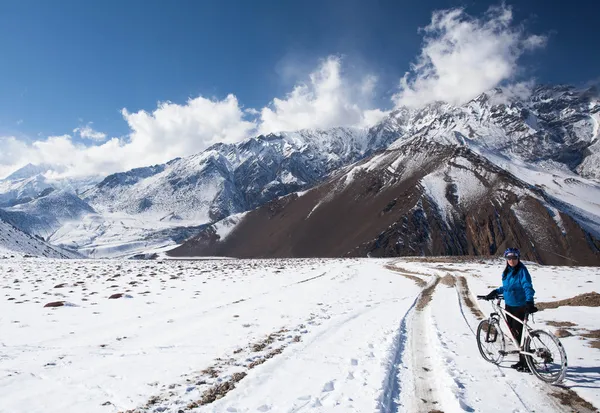 Girl on bike rides in the snow in the high mountains of the Himalayas — Stock Photo, Image