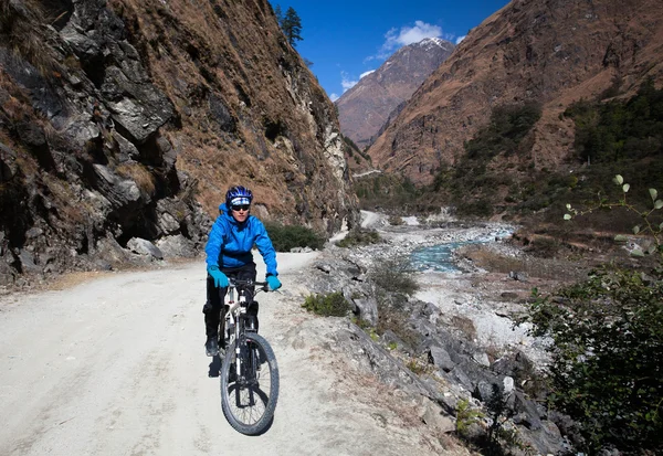 Girl cyclist in the mountains. Annapurna track Himalayas — Stock Photo, Image