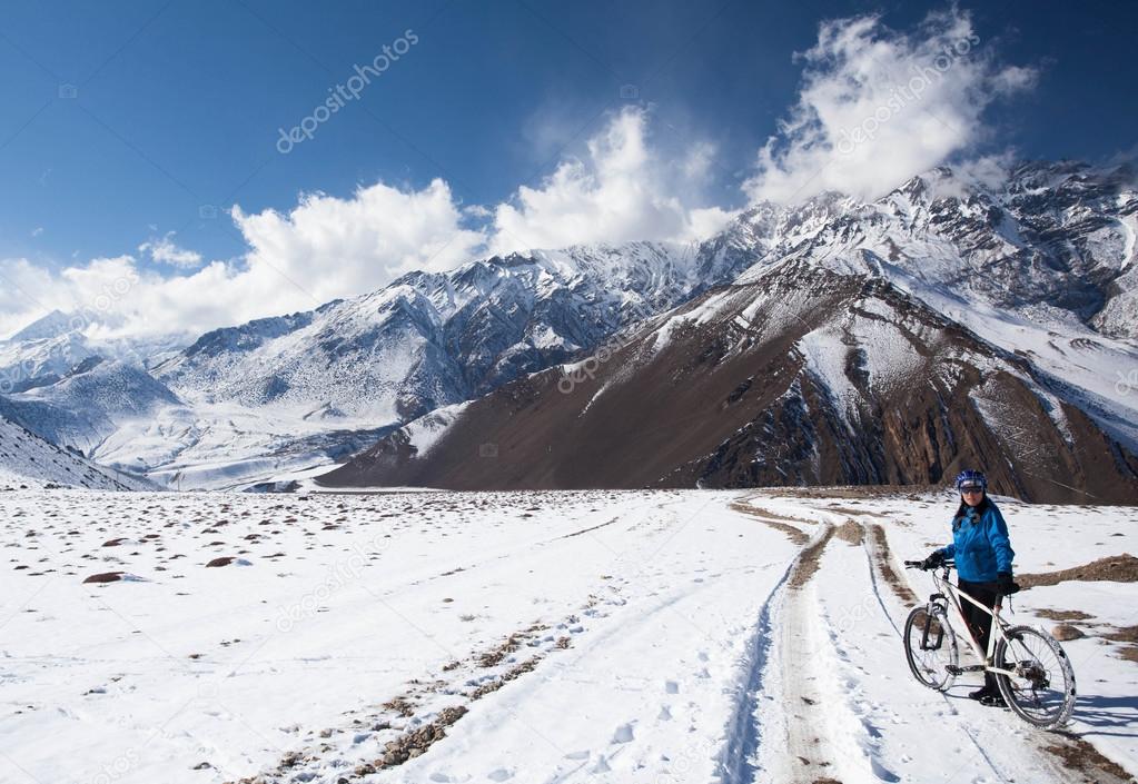 girl on bike rides in the snow in the high mountains of the Himalayas