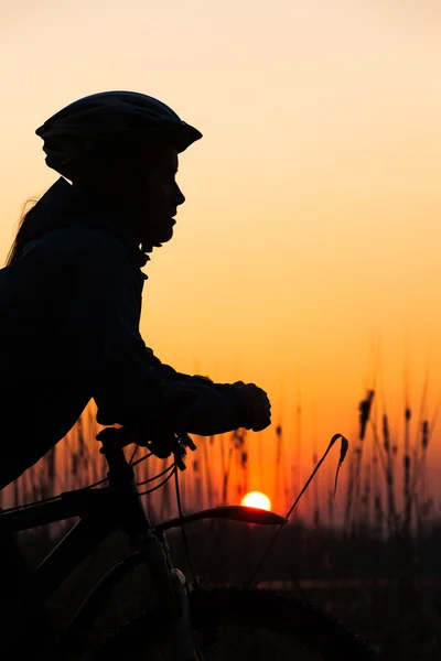 Silueta de niña al amanecer con una bicicleta —  Fotos de Stock