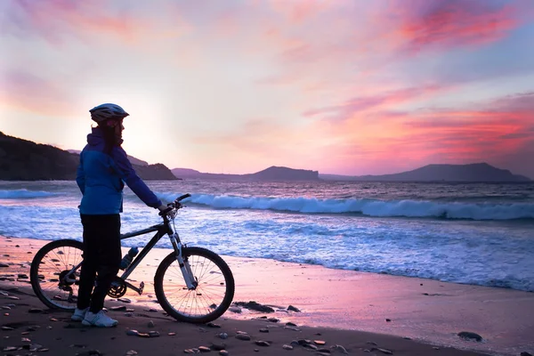 Flicka med en cykel står på stranden — Stockfoto