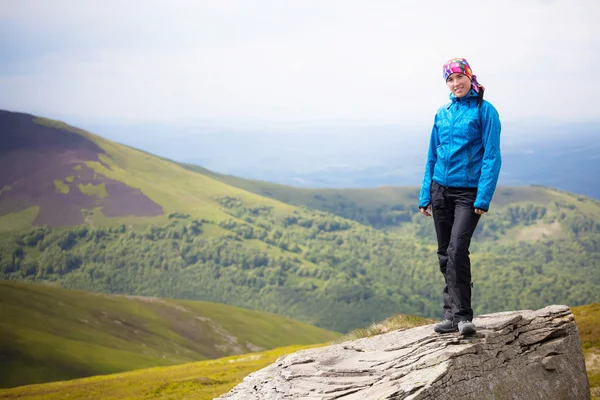 Dziewczyna stoi na wzgórzu, wśród gór z nieba — Zdjęcie stockowe