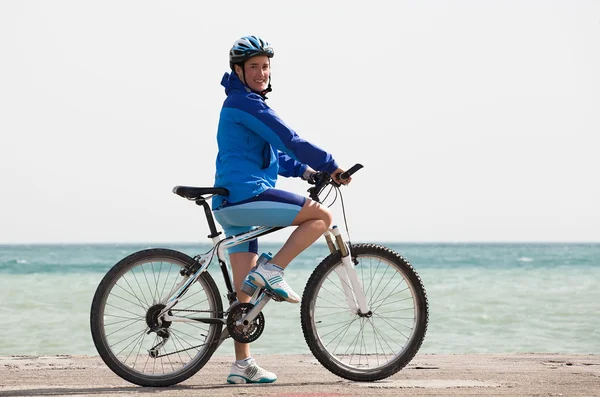 Atletisk flicka med en cykel nära havet — Stockfoto