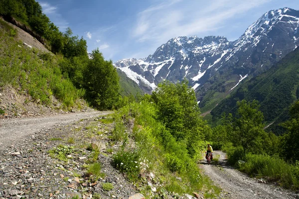 Un uomo va in bicicletta su una strada sterrata di montagna — Foto Stock