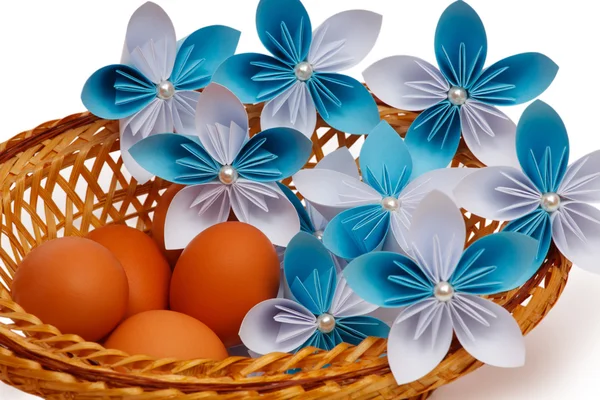 Paper flowers with eggs in a basket — Stock Photo, Image