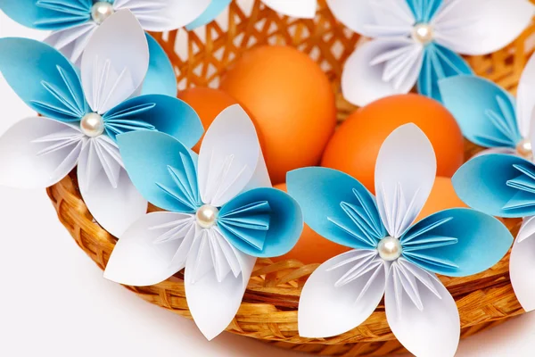 Paper flowers with eggs in a basket — Stock Photo, Image