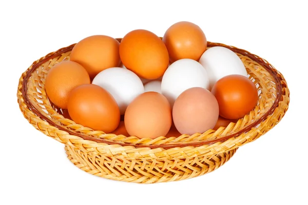 Colored and white eggs in straw basket — Stock Photo, Image