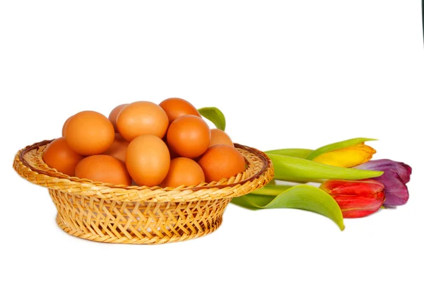 Colored eggs in a basket with tulips — Stock Photo, Image