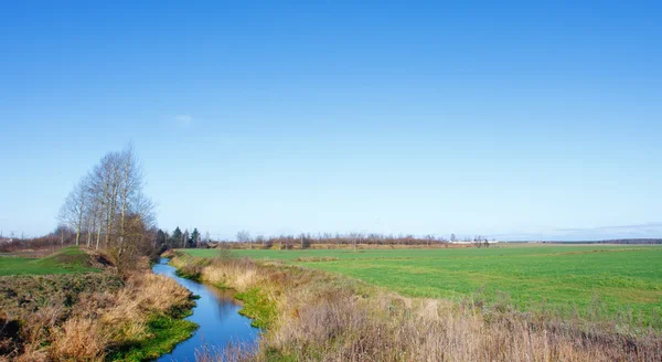 Landschaft mit Fluss und Feld in einem Dorf — Stockfoto