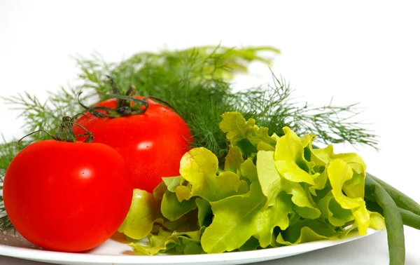 Pomidory i zieleni na białym talerzu — Zdjęcie stockowe