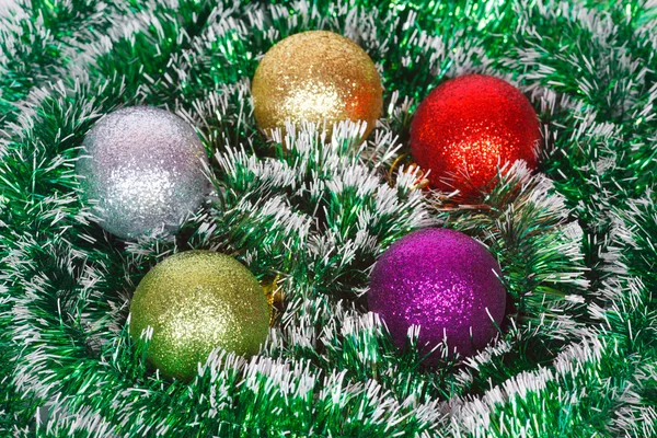 Five Christmas colored balls on the green tinsel — Stock Photo, Image