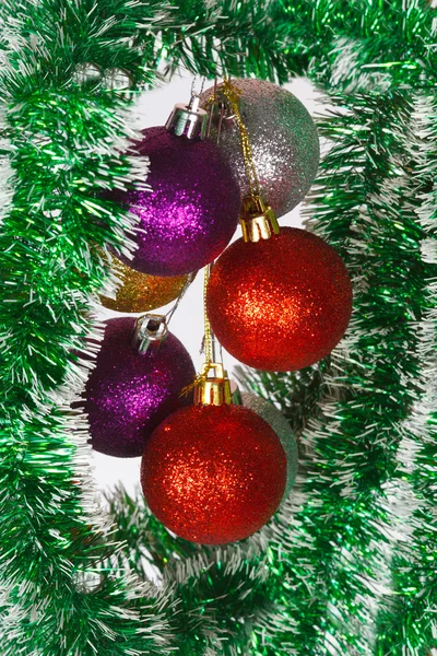 Bolas de Natal coloridas em um ouropel verde como um símbolo do Ano Novo — Fotografia de Stock