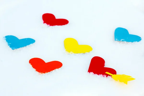 Many paper colored heart shapes in snow — Stock Photo, Image
