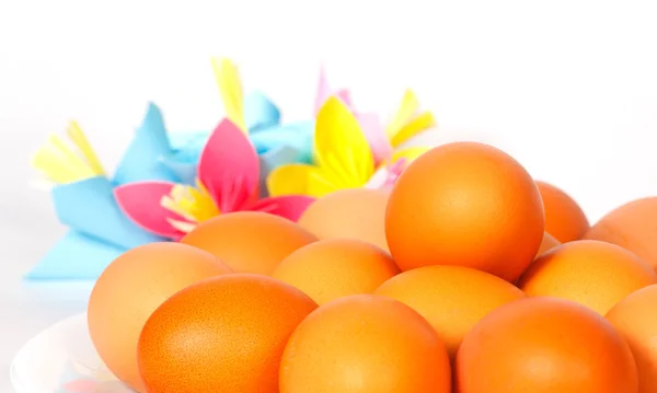 Velikonoční vejce na talíři s papírovými květinami — Stock fotografie