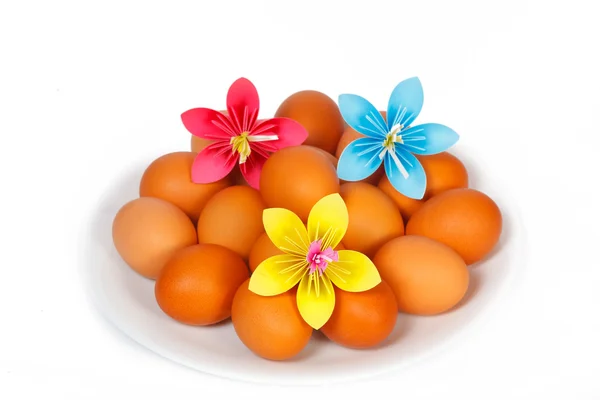 Easter eggs on the plate with a paper flowers — Stock Photo, Image