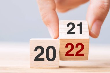 İş adamı, masa arkasında 2021 'den 2022' ye kadar yazı yazan tahta küpü tutuyor. Çözüm, strateji, çözüm, hedef, iş ve yeni yıl tatili kavramları