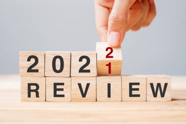 İş adamı ahşap küpü tutuyor ve masa arkasında 2021 'den 2022' ye dönüyor. Çözüm, hedef, değişim, başlangıç ve yeni yıl tatili kavramları
