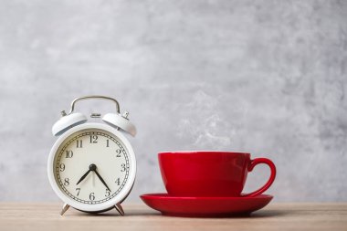 Masada sıcak espresso kahve ve klasik saat, kafede ya da sabah evde kırmızı kahve fincanı. Etkinlik, günlük rutin, sabah, egzersiz ve iş hayatı dengesi kavramı