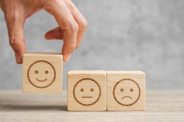 Elele tutuşan bir adam yüz bloğu. Müşteri, kullanıcı değerlendirmeleri için Emoticon 'u seçer. Hizmet derecesi, sıralama, müşteri değerlendirmesi, memnuniyet, ruh hali, değerlendirme ve geri bildirim kavramı