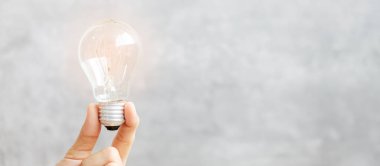 Arka planda el ele tutuşan ampul. Yeni Fikirler, Yaratıcı, Yenilik, Hayal gücü, İlham, Çözüm, Strateji ve hedef kavramı