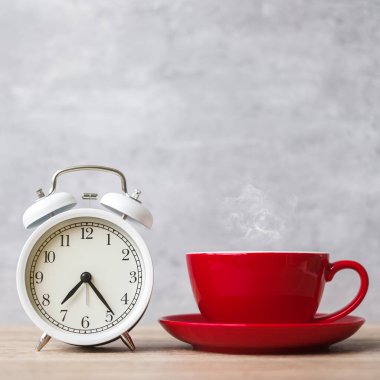 Masada sıcak espresso kahve ve klasik saat, kafede ya da sabah evde kırmızı kahve fincanı. Etkinlik, günlük rutin, sabah, egzersiz ve iş hayatı dengesi kavramı