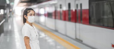 Tren beklerken koruyucu yüz maskesi takan kadın Coronavirus bükülmesini önlüyor. Toplu taşıma. Sosyal uzaklık, covid-19 salgını altında yeni normal ve güvenlik
