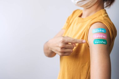 woman showing plaster after receiving covid 19 vaccine. Vaccination, herd immunity, side effect, booster dose, vaccine passport and Coronavirus pandemic clipart