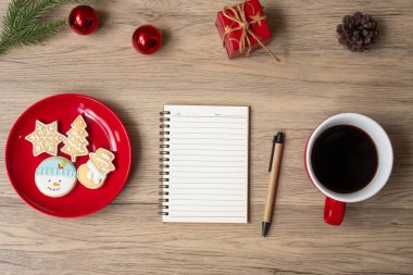 Boş defter, sade kahve fincanı, Noel kurabiyeleri ve tahta masa üzerindeki kalem, üst manzara ve fotokopi alanı. Xmas, Mutlu Yıllar, Hedefler, Kararlılık, Yapılacaklar listesi, Strateji ve Planlama konsepti