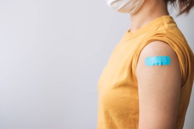 woman showing bandage after receiving covid 19 vaccine. Vaccination, herd immunity, side effect, booster dose, vaccine passport and Coronavirus pandemic clipart