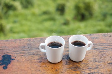 couple White mug of hot coffee or tea on wooden table in the morning with mountain and nature background