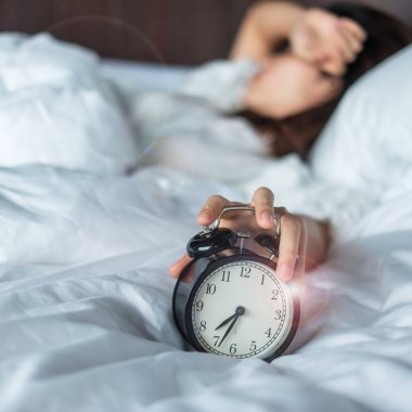 Asyalı bir kadın sabahın köründe alarmlı saatle yatakta yatıyor. Genç bir kadın yatak odasında uyuyor. Huzursuz, uykusuz, uykusuz, endişeli ve stresli kavramlar