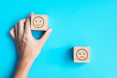 Elele tutuşan bir adam yüz bloğu. Müşteri, kullanıcı değerlendirmeleri için Emoticon 'u seçer. Hizmet derecesi, sıralama, müşteri değerlendirmesi, memnuniyet, değerlendirme ve geri bildirim kavramı