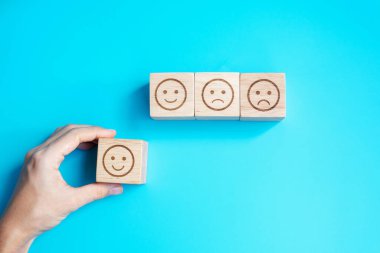 Elele tutuşan bir adam yüz bloğu. Müşteri, kullanıcı değerlendirmeleri için Emoticon 'u seçer. Hizmet derecesi, sıralama, müşteri değerlendirmesi, memnuniyet, değerlendirme ve geri bildirim kavramı