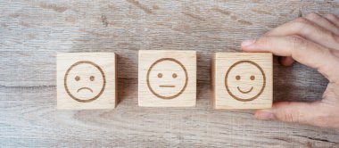 Elele tutuşan bir adam yüz bloğu. Müşteri, kullanıcı değerlendirmeleri için Emoticon 'u seçer. Hizmet derecesi, sıralama, müşteri değerlendirmesi, memnuniyet, değerlendirme ve geri bildirim kavramı