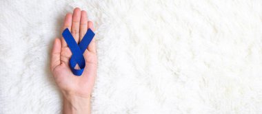 March Colectal Kanser Farkındalığı Ayı, Koyu Mavi Kurdele 'yi yaşayan ve hastalıkları desteklemek için elinde tutan adam. Sağlık, umut ve Dünya Kanser Günü konsepti