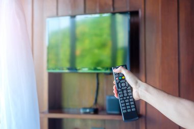 Ev veya lüks oteldeki modern odadaki Smart TV 'yi ayarlamak için uzaktan kumanda kullanılıyor.