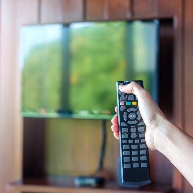 Ev veya lüks oteldeki modern odadaki Smart TV 'yi ayarlamak için uzaktan kumanda kullanılıyor.