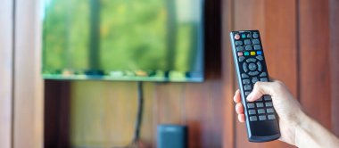 Ev veya lüks oteldeki modern odadaki Smart TV 'yi ayarlamak için uzaktan kumanda kullanılıyor.