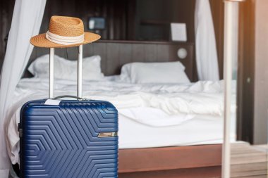 Kapı açıldıktan sonra modern otel odasında şapkalı mavi bavul. Seyahat, hizmet, yolculuk, seyahat, yaz tatili ve tatil kavramları