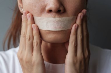 Ağzı yapışkan bantla mühürlenmiş kadın. İfade özgürlüğü, basın özgürlüğü, İnsan hakları, Protesto diktatörlüğü, demokrasi, özgürlük, eşitlik ve kardeşlik kavramları