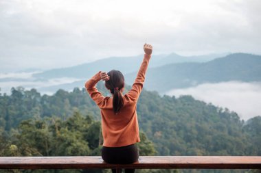 Happy woman relaxing and looking mountain view at countryside home or homestay in the morning. Vacation, blogger, SoloTravel, journey, trip and relaxing concept