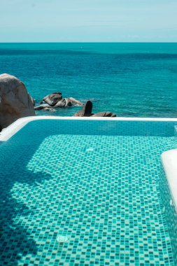 Okyanus kıyısındaki lüks oteldeki sonsuz havuz, tropikal tatil köyü. Rahatlama, yaz, seyahat, tatil, tatil ve hafta sonu konsepti