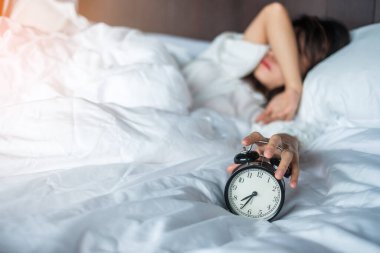 Asyalı bir kadın sabahın köründe alarmlı saatle yatakta yatıyor. Genç bir kadın yatak odasında uyuyor. Huzursuz, uykusuz, uykusuz, endişeli ve stresli kavramlar