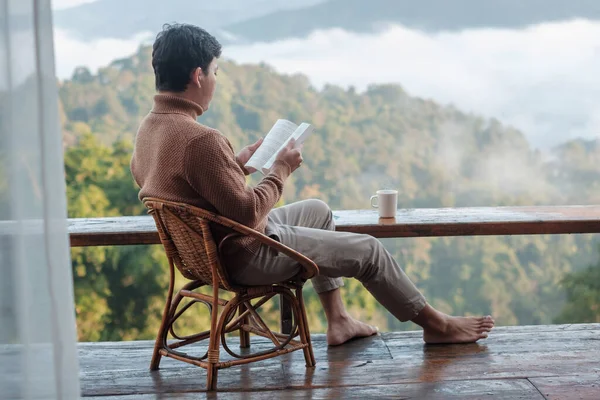 Jovem Homem Lendo Livro Perto Janela Olhando Para Vista Montanha — Fotografia de Stock