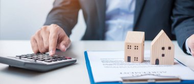 Evle sözleşme imzalarken hesap makinesi kullanan bir adam. Kontrat sözleşmesi, gayrimenkul, alım-satım ve sigorta kavramları